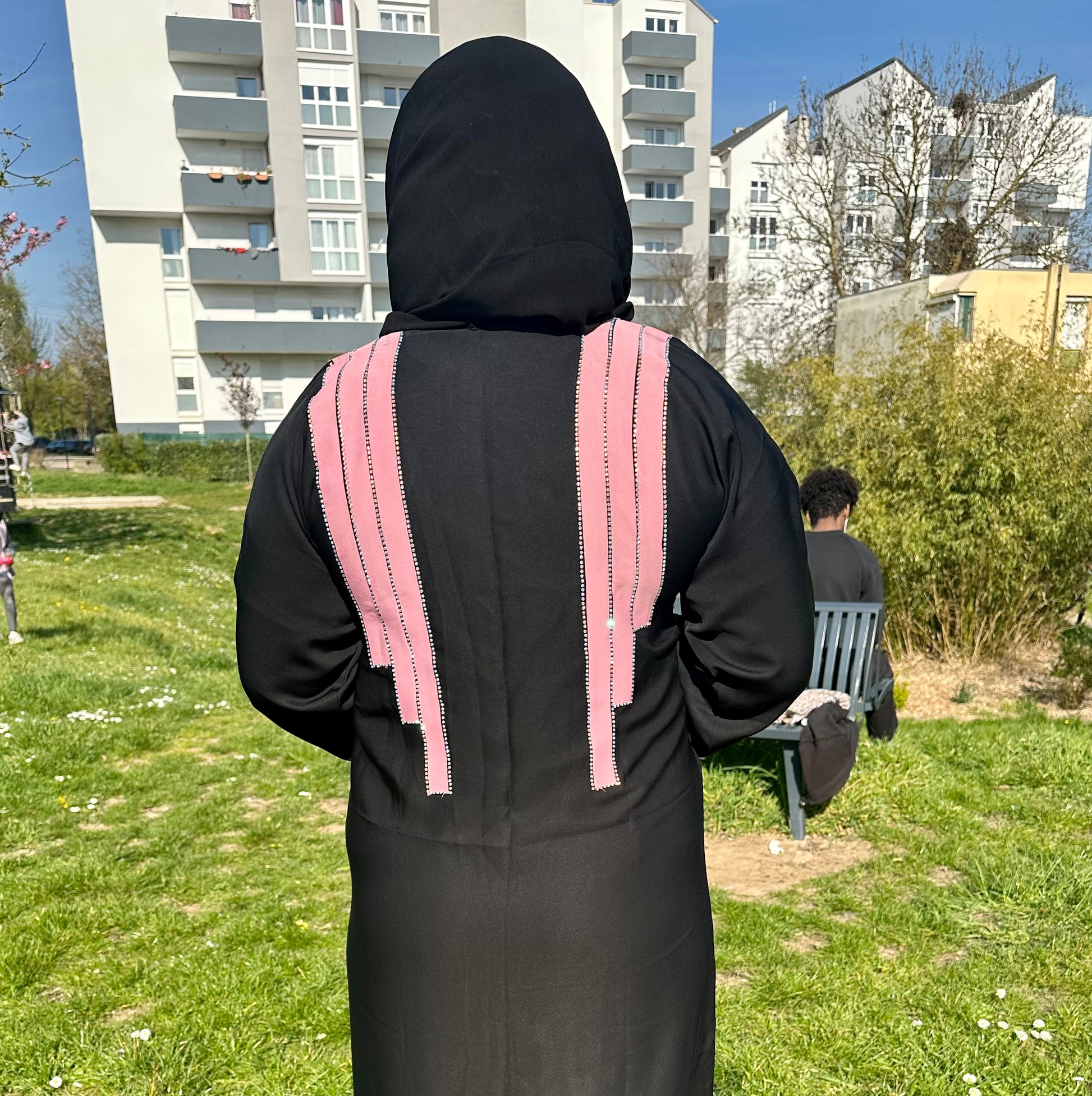 a person in a hooded jacket standing in the grass 